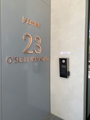 Une porte avec l’inscription « Jasmine, 23, rue O’Sullivan » et un système de verrouillage à clavier.