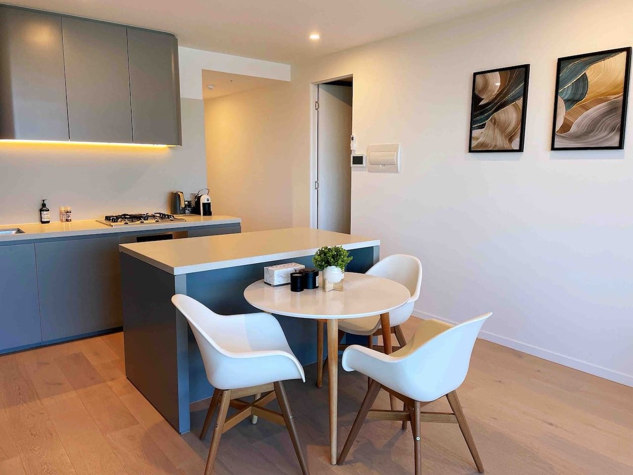 A modern kitchen with a central island, white chairs, and a small table.