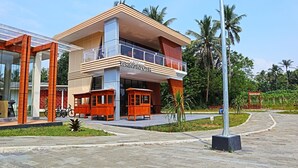 Um hotel moderno com estrutura em dois andares, uma varanda e uma placa indicando ser um 'Restoran Wringinputih'.