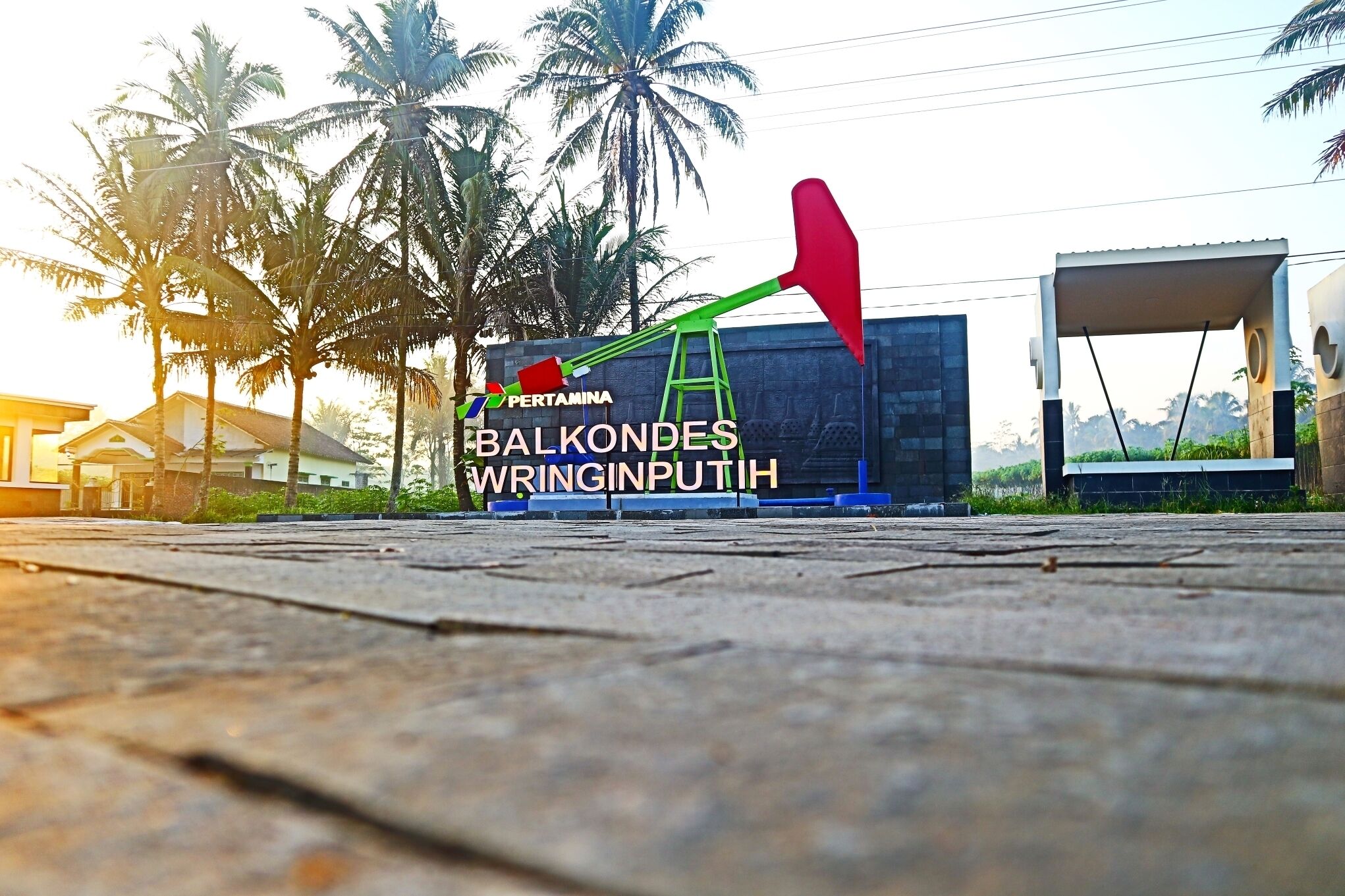 A wooden deck with a palm tree and a red and green object in the background.