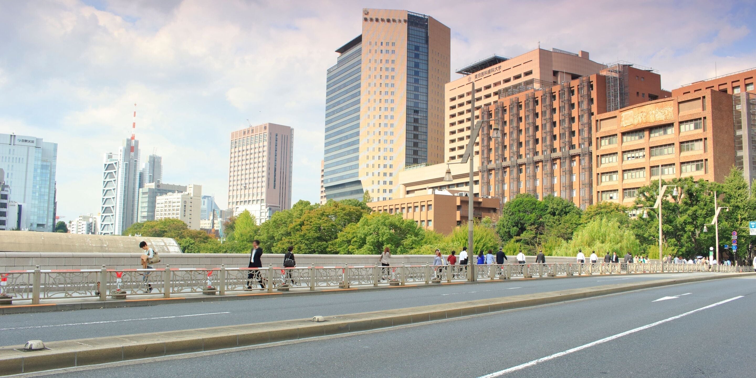 A cityscape with modern buildings, a pedestrian bridge, and a clear sky.