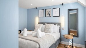 A bedroom with a bed, a bedside table, a mirror, and artwork on the wall. - Spacious Apartment, 1 Minute from Seafront (Paignton)