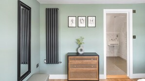 Un bagno con uno specchio, un termosifone, un armadietto in legno e un'opera d'arte incorniciata appesa al muro.