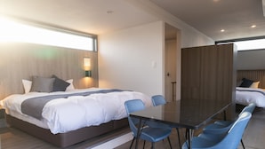 Una habitación de hotel moderna con una cama grande, una mesa de comedor y sillas azules.