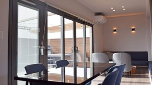 Un comedor moderno con un separador de vidrio, una mesa oscura y sillas azules.