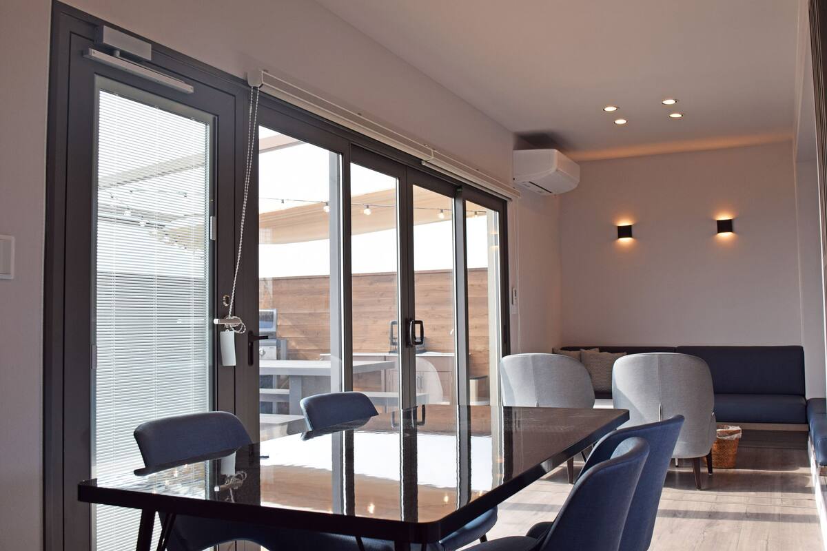 A modern dining area with a glass partition, a dark table, and blue chairs.