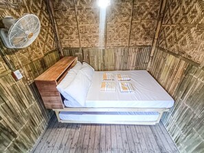 A compact room with a bed, a wooden bench, and a wall-mounted fan. - Glamper Grove Real Magra 2 (Real)