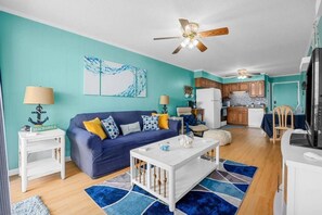 A living room with a blue sofa, a white coffee table, and a ceiling fan.