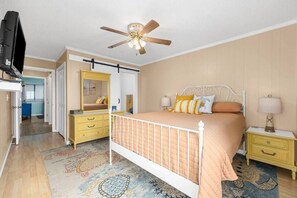 A bedroom with a bed, nightstands, a dresser, a ceiling fan, and a television.