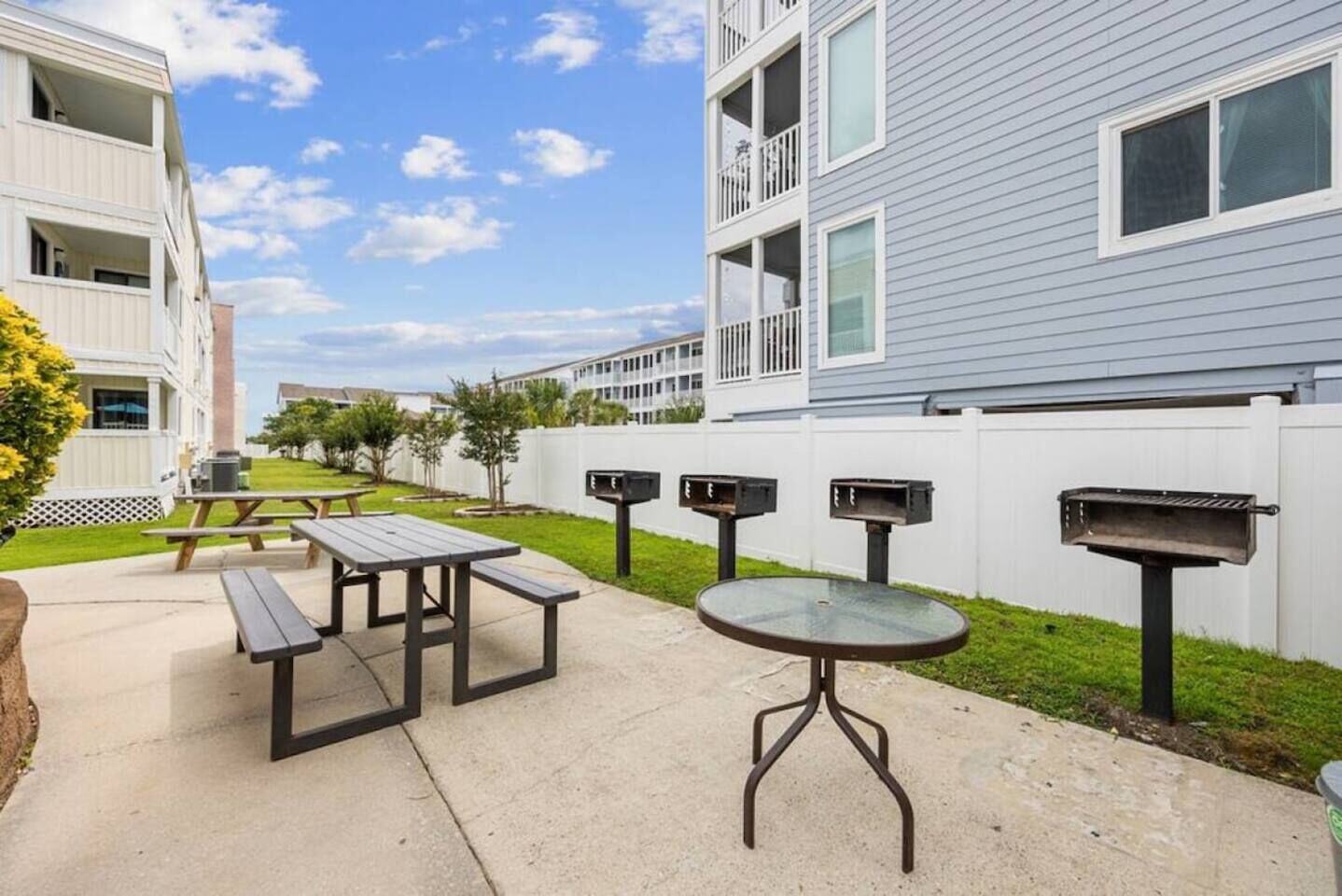An outdoor patio area with picnic tables and a barbecue grill.