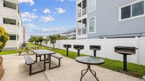 An outdoor patio area with picnic tables and a barbecue grill. - Blue's Oceanview 2Bdrm- Pool, Peaceful Balcony (Myrtle Beach)