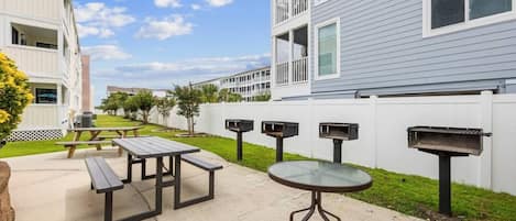 An outdoor patio area with picnic tables and a barbecue grill.