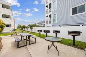 An outdoor patio area with picnic tables and a barbecue grill.
