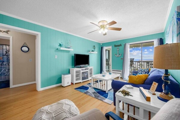 A living room with a television, white cabinet, blue sofa, and a ceiling fan.