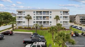 A multi-story residential building with a parking lot in front. - Blue's Oceanview 2Bdrm- Pool, Peaceful Balcony (Myrtle Beach)