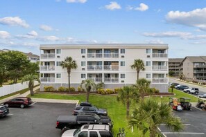 A multi-story residential building with a parking lot in front.