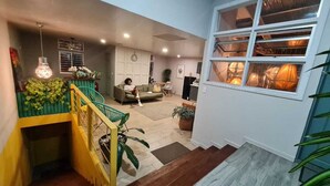 A spacious living area with a staircase, a sofa, and a dining area. - Otoya1907 Hotel (San José)