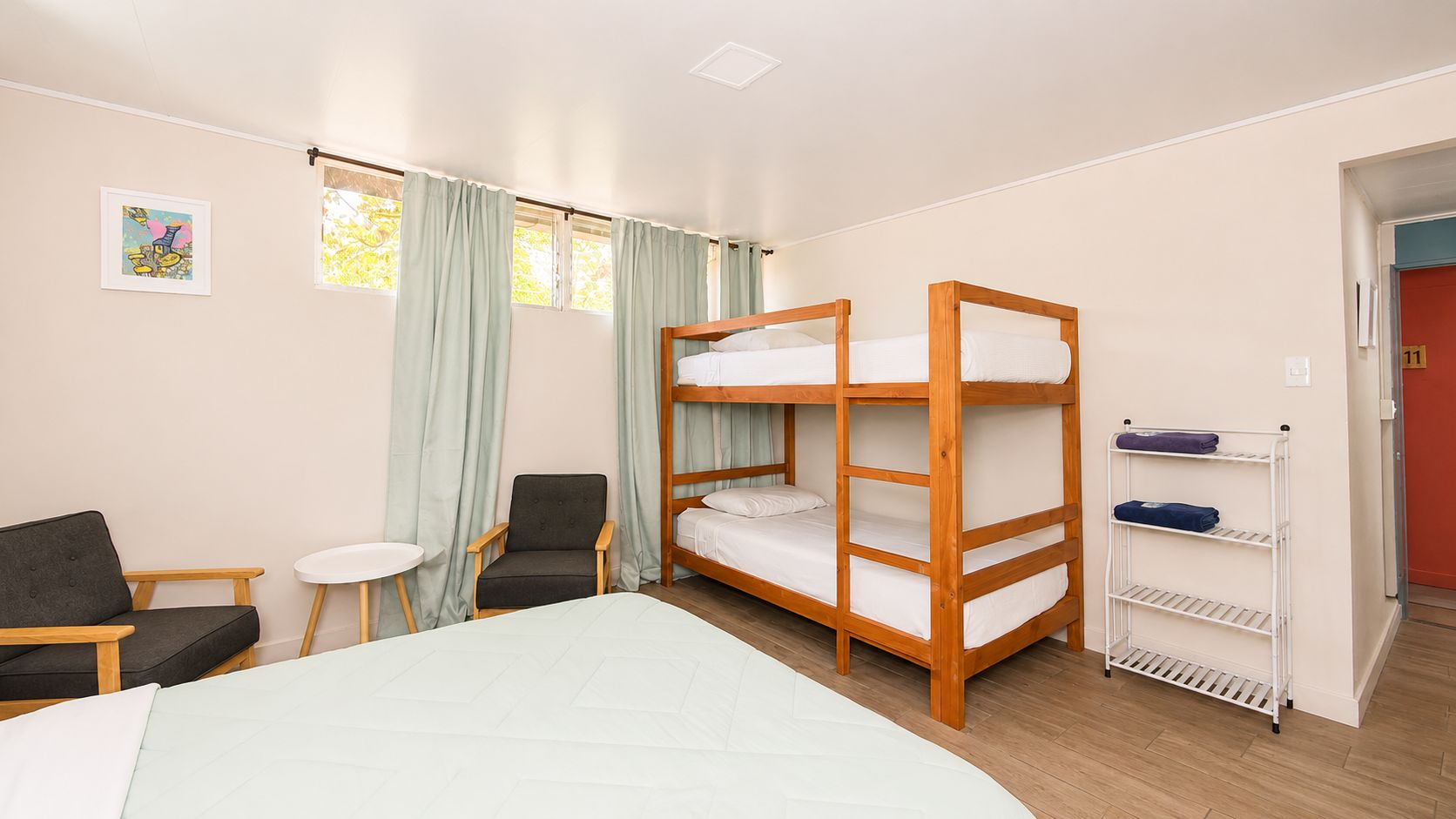 A room with bunk beds, a chair, a small table, and a shelf with towels.