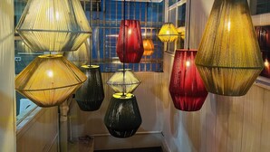 A series of hanging lamps with a geometric design, suspended from a ceiling with a skylight above. - Otoya1907 Hotel (San José)