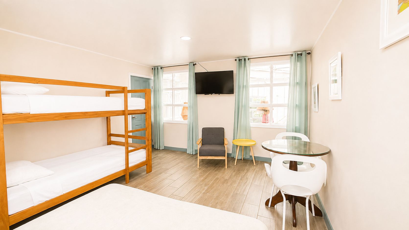 A room with bunk beds, a desk, a chair, and a television.