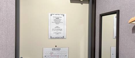 A hotel room door with a notice about room key usage and an emergency exit map.