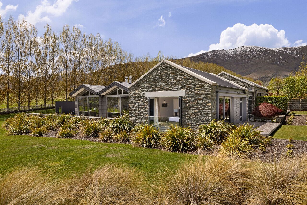 A modern house with a stone facade, large windows, and a well-maintained garden.