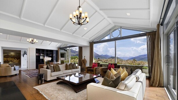 A spacious living room with a large window offering a mountain view, a chandelier, and a modern interior design. - Kumanu - Crown Range (Arrow Junction)