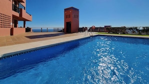 Uma piscina com céu azul límpido e um sol ao fundo.