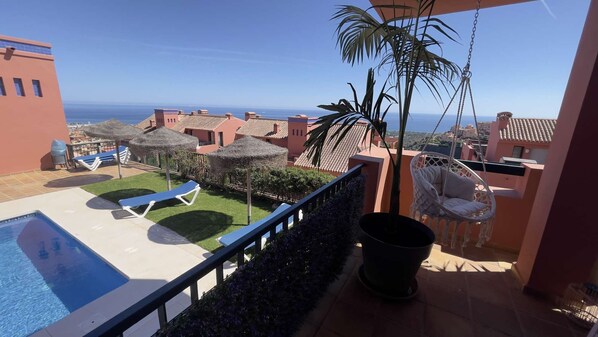 Un balcon avec une piscine, des chaises longues et une vue sur la mer.