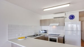 Une cuisine moderne avec des carreaux blancs, un four encastré, un four à micro-ondes et un réfrigérateur.