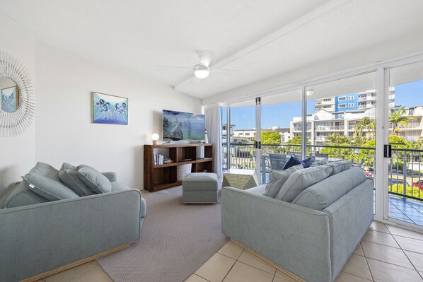 Relax in this stylish living room with a flat-screen TV, comfortable sofas, and a balcony with a residential view.