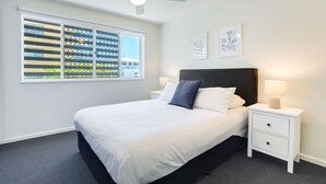 A bedroom with a bed, a nightstand, a ceiling fan, and a window with blinds. - 2 Bedroom Apartment Sea View Second Floor (Sunshine Coast)