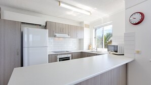 Een moderne keuken met een centraal eiland, ingebouwde apparatuur en een groot raam dat voor natuurlijk licht zorgt.