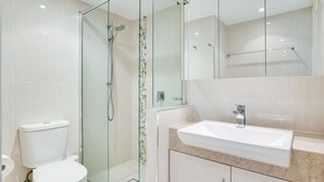 A modern bathroom with a glass-enclosed shower, a white sink, and a toilet.