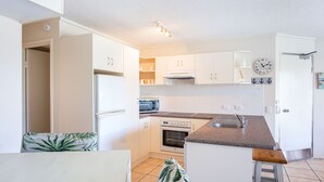 A compact kitchen with white cabinets, a microwave, an oven, and a sink.