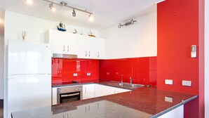 Une cuisine moderne avec des meubles blancs, un pare-feu rouge et un plan de travail en granit.