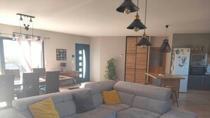 Un salon moderne avec un canapé d’angle gris, une table basse en bois et des luminaires suspendus.