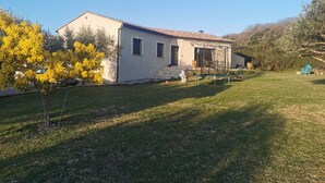 Une maison de plain-pied avec un toit en tuiles, un petit porche et une cour gazonnée.