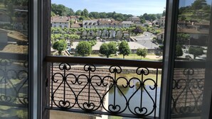 Un balcon doté de balustrades en fer forgé, donnant sur un quartier résidentiel avec des maisons et des arbres.