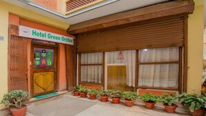 A hotel entrance with a sign reading "Hotel Green Orchid," a wooden door, and potted plants in front. - MeroStay 211 Hotel DN (Kathmandu)