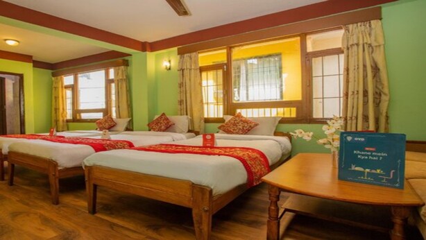 A hotel room with three wooden beds, a small table, and a window with curtains. - MeroStay 211 Hotel DN (Kathmandu)