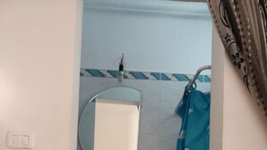 Un bagno con lavandino, specchio e tenda da doccia.