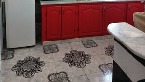 Una cucina con mobili rossi, un frigorifero bianco, un forno a microonde e un lavello.