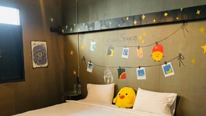 Un lit bien fait, avec du linge de lit blanc, un canard en peluche jaune et une guirlande de décorations en forme d’étoiles accrochée au mur.