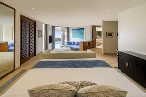 Relax in a spacious room with a large bed, sofa, and flat-screen TV, offering a view of the outdoors.