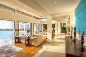 Relax in this open living area with a sofa, coffee table, and rug, offering a clear view of the adjacent dining space and the sea beyond.