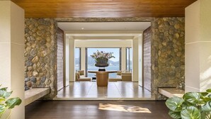 A spacious hallway with a stone wall, a wooden ceiling, and a view of the sea. - Villa Fah Sai (Kamala)