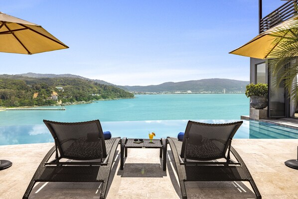 Relax on the patio with a serene view of the lake, surrounded by lush greenery and hills.