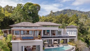 A modern two-story house with a swimming pool, large windows, and a lush garden. - Villa Fah Sai (Kamala)