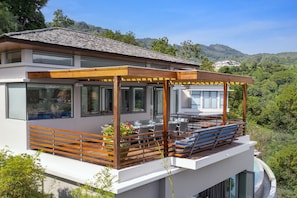 Enjoy a serene view of the lush hillside from the spacious outdoor deck with a pergola.